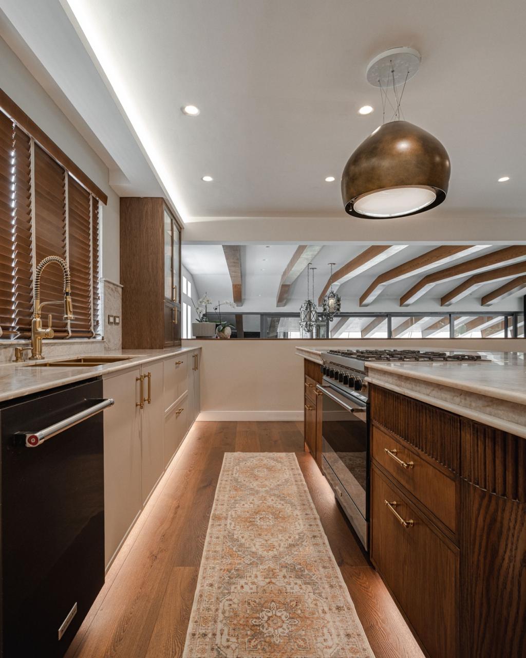 Cocina de madera con isla, iluminación arquitectónica y electrodomésticos