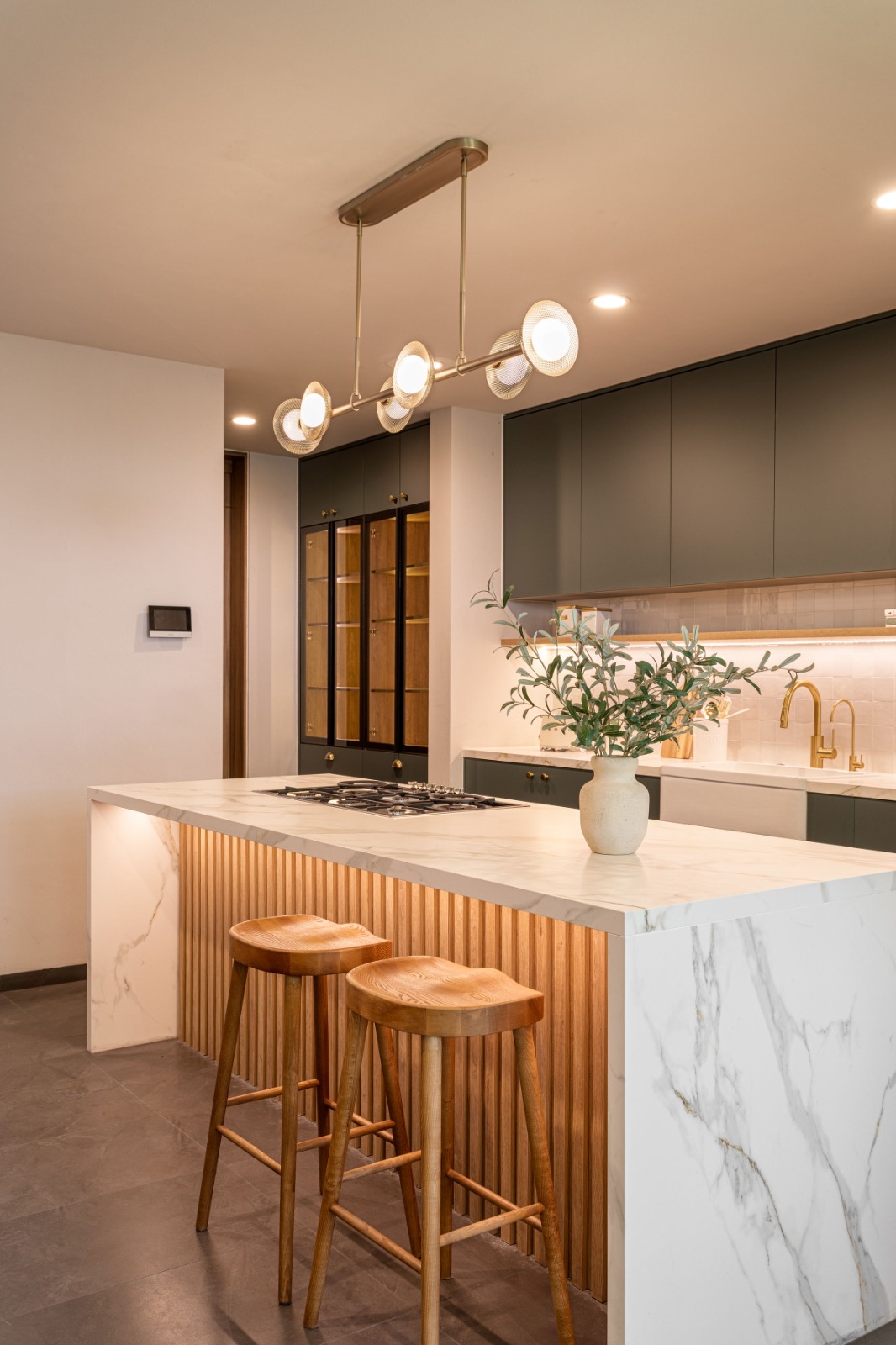 Detalle de cocina verde con isla revestida de mármol y madera